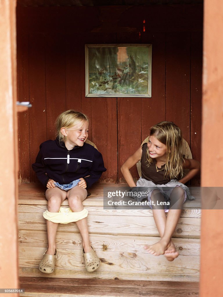 Girls sitting in outhouse