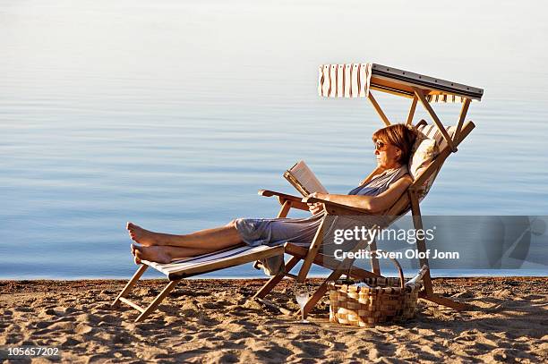 woman relaxing on chair and reading - beach book reading stockfoto's en -beelden