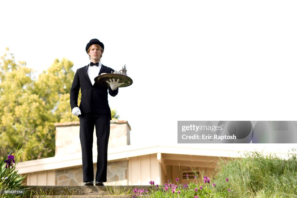 Caucasian man in tuxedo carrying tray