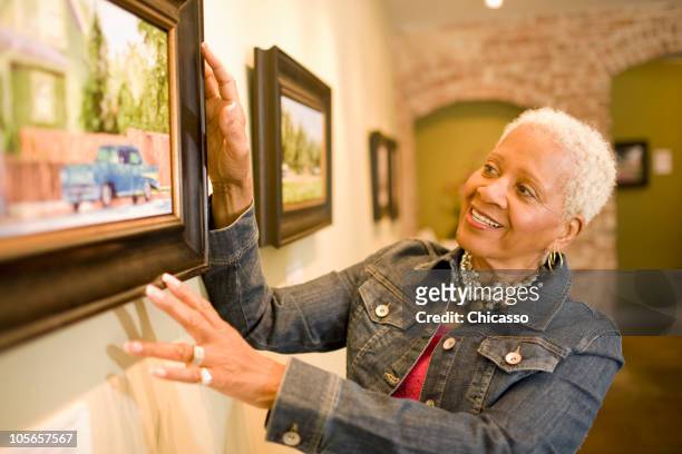black woman admiring painting in gallery - owner stand stockfoto's en -beelden