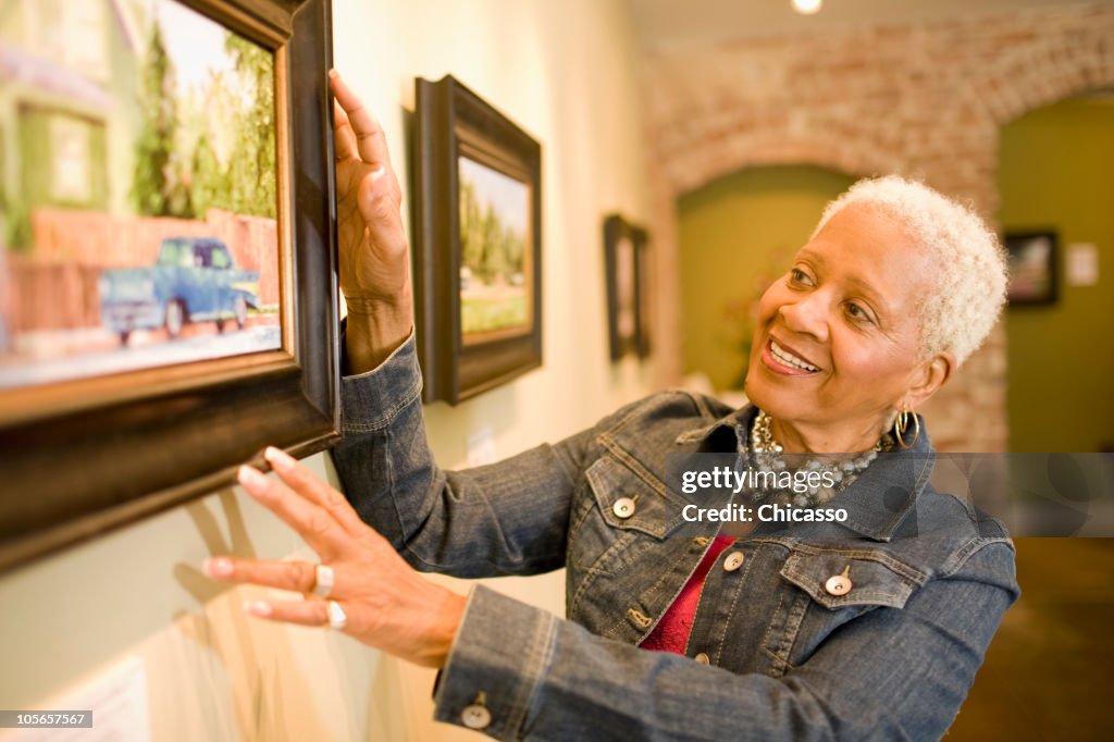 Black woman admiring painting in gallery