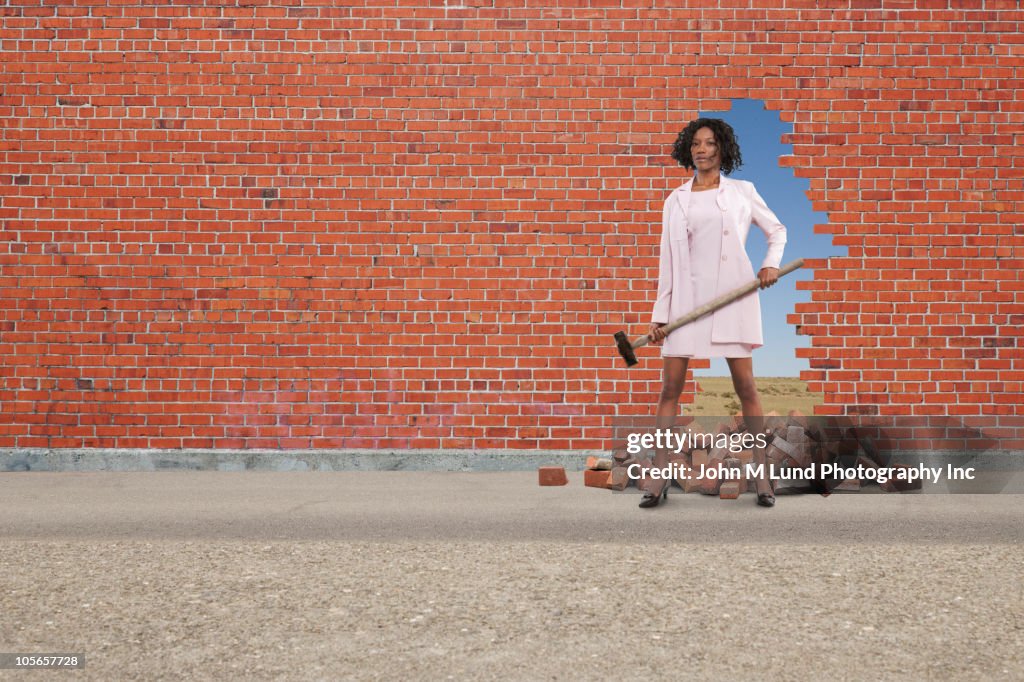 Black businesswoman breaking through brick wall