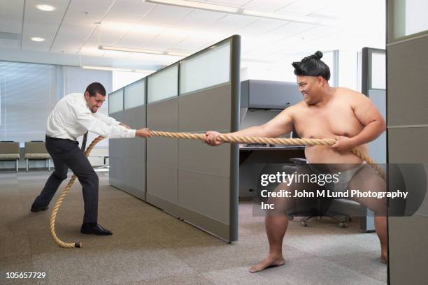 businessman playing tug-of-war with sumo wrestler - 綱引き ストックフォトと画像