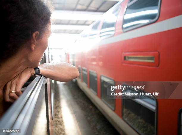 italy, woman looking through train window at train station - holiday hours stock-fotos und bilder