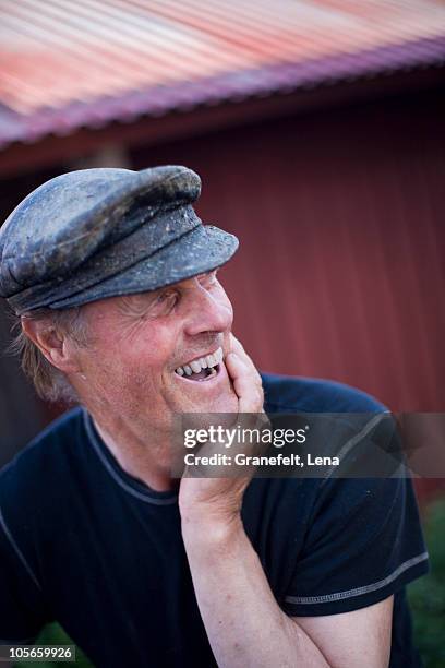 sweden, stockholm archipelago, fisherman laughing, outdoors - baker boy cap stock-fotos und bilder