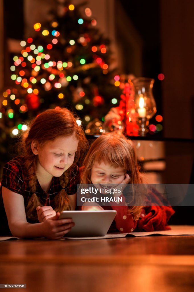 Sisters using tablet PC on floor during Christmas