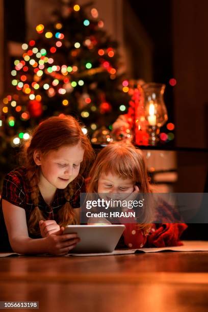 sisters using tablet pc on floor during christmas - family game night stock pictures, royalty-free photos & images