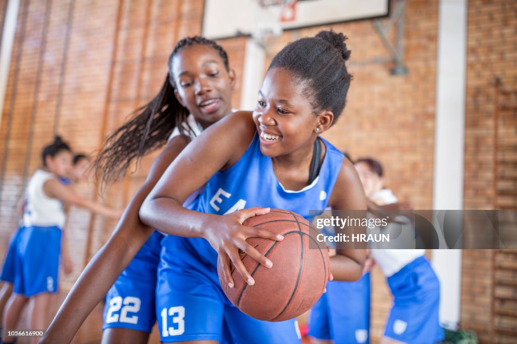 Female defending basketball from opponent
