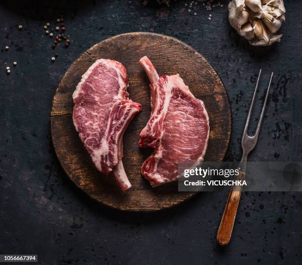 marbled raw pork chops of porco iberico meat on round cutting board with meat knife. french racks - cutlet stockfoto's en -beelden