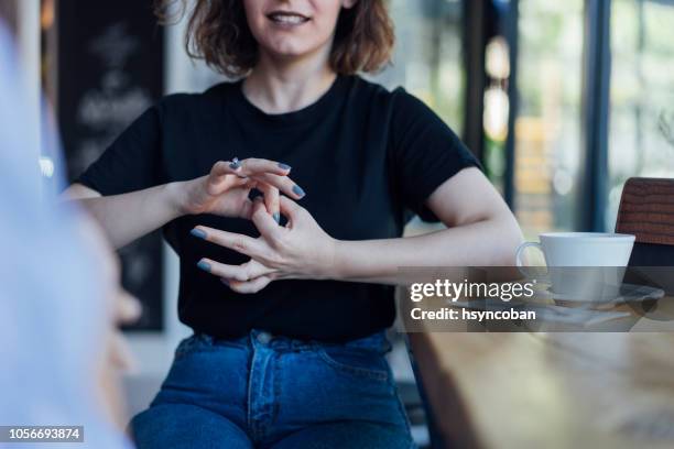 dos mujeres jóvenes hablan en lengua de signos - american sign language fotografías e imágenes de stock