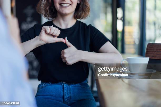 two young woman speak in sign language - american sign language stock pictures, royalty-free photos & images