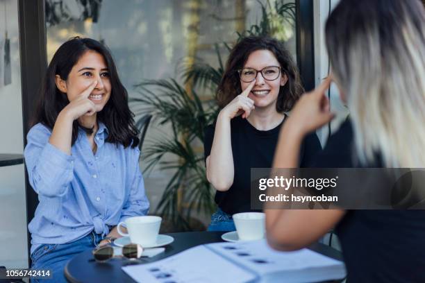 young women learn to speak in sign language - american sign language stock pictures, royalty-free photos & images