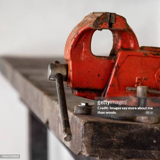 close up of a very red old vise over a work bench. still life. - vice grip stock pictures, royalty-free photos & images