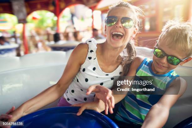 brother and sister enjoying spinning carousel - theme park imagens e fotografias de stock