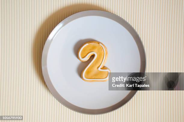 gold colored number 2 cookie on a white plate - second photos et images de collection