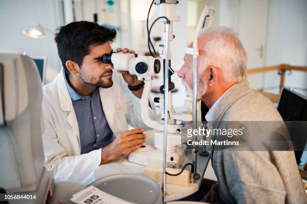 old men having an eye exam at ophthalmologist's office. - eye test equipment imagens e fotografias de stock