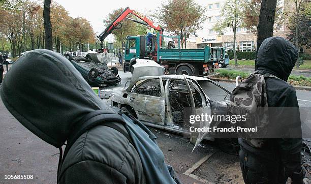 Burnt out car lies in the street after clashes with riot police officers, unseen, in Nanterre on Oct 19 in Paris, France. As French oil workers...