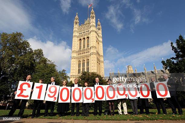 Thirteen leaders of the UK's public sector unions hold up placards displaying the figure 19 billion GBP, which is the tax revenue avoided by UK...