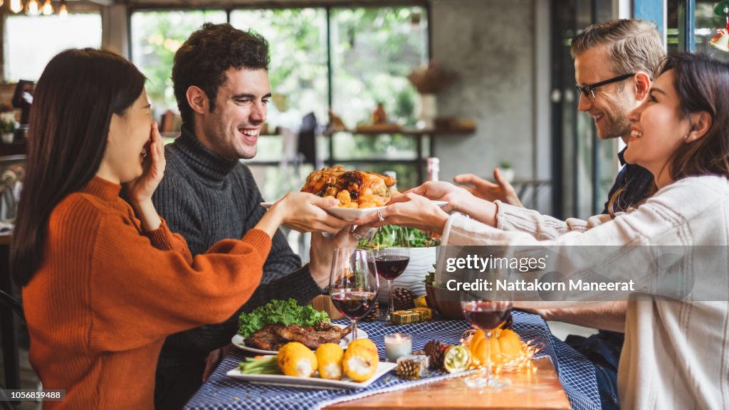Group of young people celebrating Christmas party dinner with clinking glass of wine