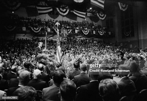 View of American senator Robert F Kennedy , on a podium surrounded by supporters, as he speaks into microphones at an unspecifed rally during his...