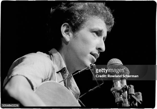 Close-up of American musician Bob Dylan as he plays acoustic guitar during a performance at the Newport Folk Festival, Newport, Rhode Island, July...