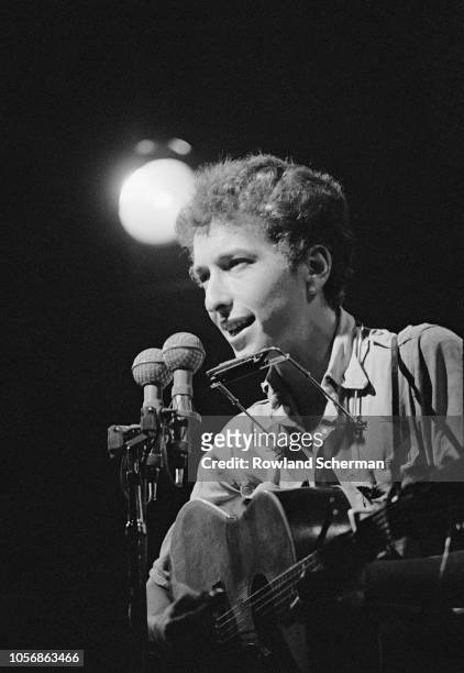 View of American musician Bob Dylan as he plays acoustic guitar during a performance at the Newport Folk Festival, Newport, Rhode Island, July 1963.