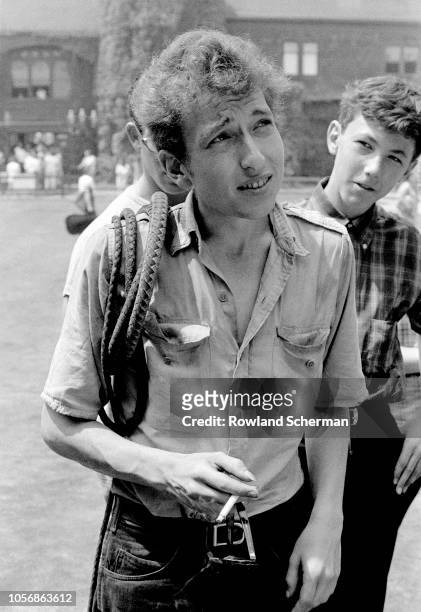 View of American musician Bob Dylan , along with an unidentified young man, on the grass of the tennis court at the Newport Casino during the Newport...