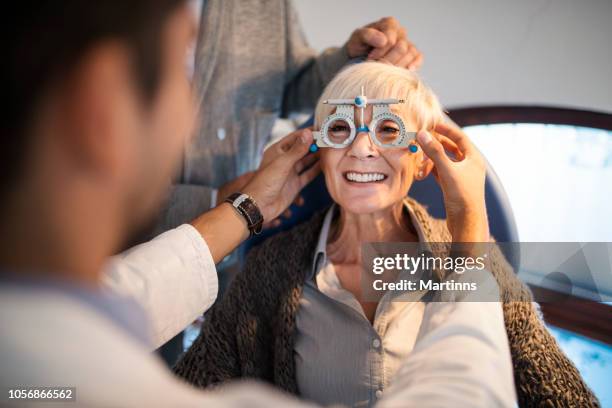 joven sonriente oftalmólogo comprobación de vista de una mujer. - aparato de prueba ocular fotografías e imágenes de stock