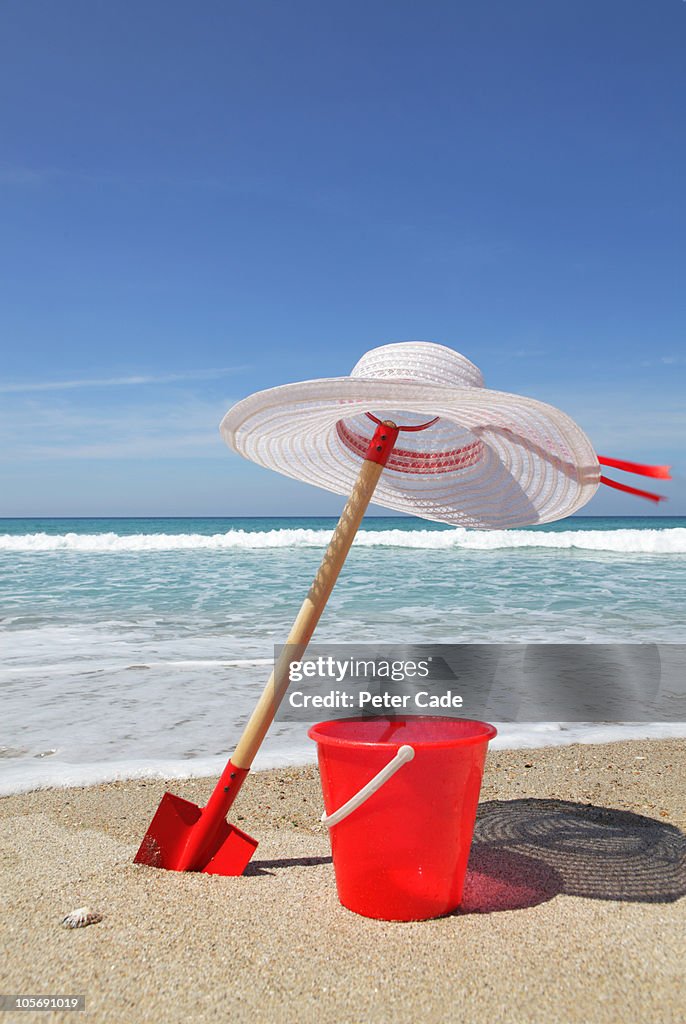 Bucket, spade and hat on beach next to sea