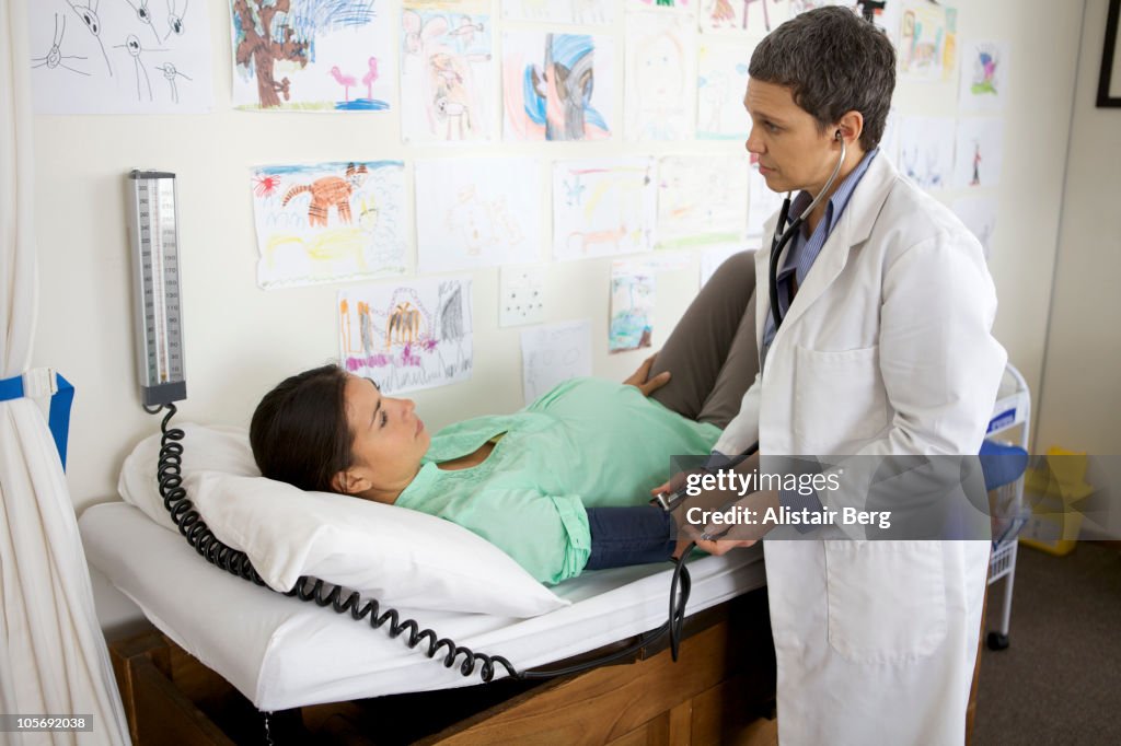 Doctor checking blood pressure of pregnant woman