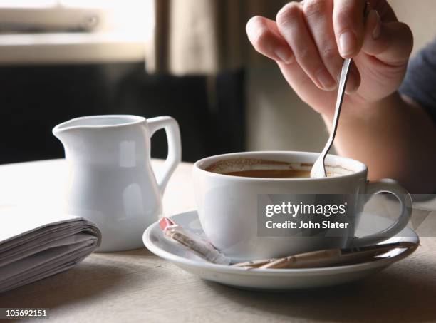 woman stirring her coffee at table - stirring stock-fotos und bilder