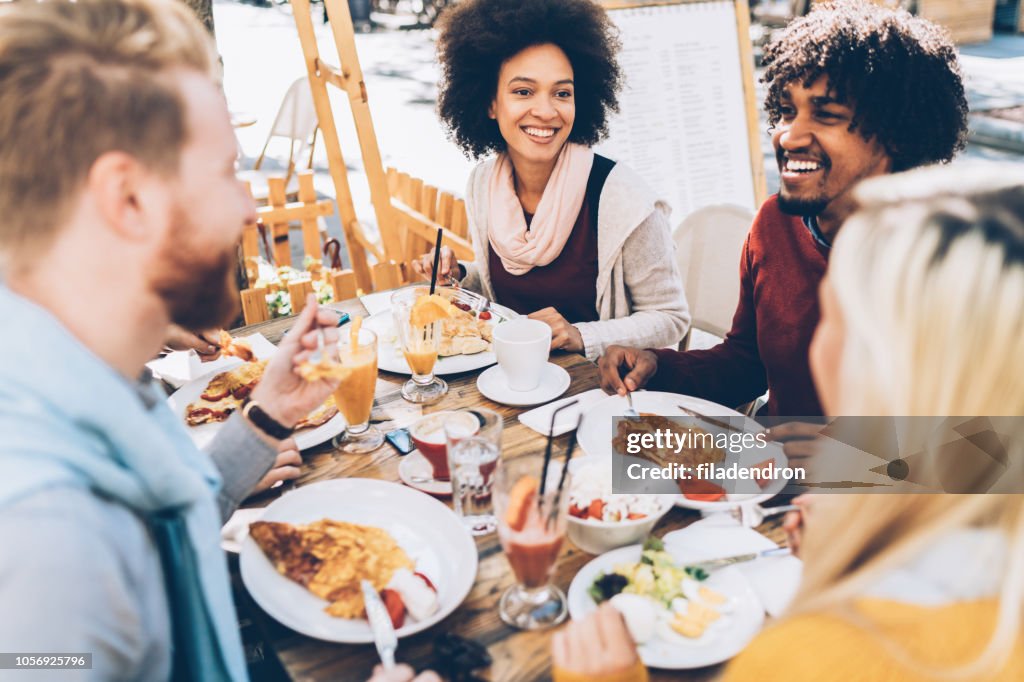 Grupo étnico multi de amigos comiendo el almuerzo en un restaurante