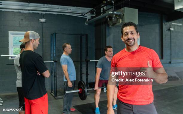 the mature latino man posing in front of the group of his friends, athletes of different ages, body types and abilities, in the gym - alex potemkin or krakozawr latino fitness stock pictures, royalty-free photos & images