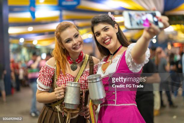 girls friends taking a selfie on celebratory toast at beer fest - traditional festival imagens e fotografias de stock