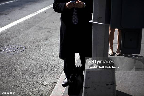 Man types on his blackberry while waiting for a bus in Midtown Manhattan, home to many of the world's banks on April 9, 2009 in New York City.
