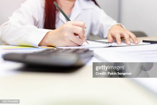 close up right hand female with pencil on notebook - atestado imagens e fotografias de stock