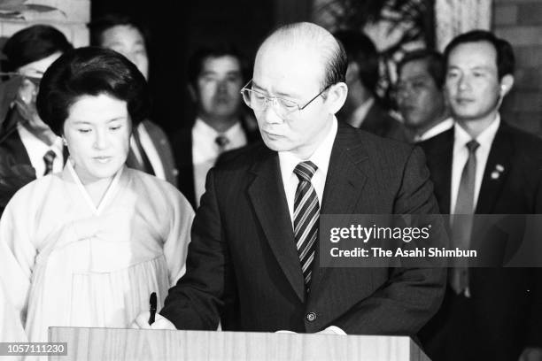 South Korean President Chun Doo-hwan signs while his wife Lee Soon-ja watches prior to their luncheon at the prime minister's official residence on...