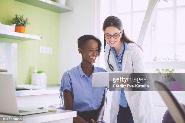 arzt beratung ihrer patientin - caucasian doctor and nurse using tablet computer stock-fotos und bilder