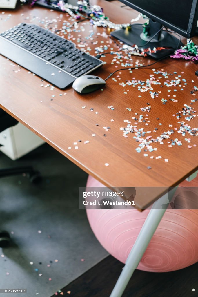 Desk with confetti and streamers on computer after a birthday party