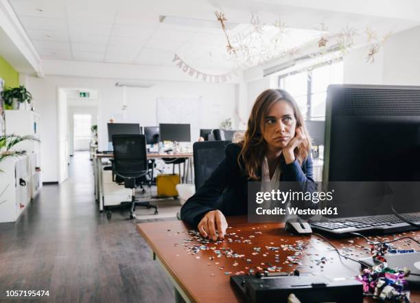 frustrated businesswoman sitting at desk, full of confetti - hangover stock-fotos und bilder