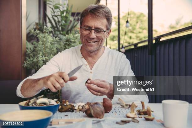 portrait of happy man slicing orange bolete - mushroom types stockfoto's en -beelden