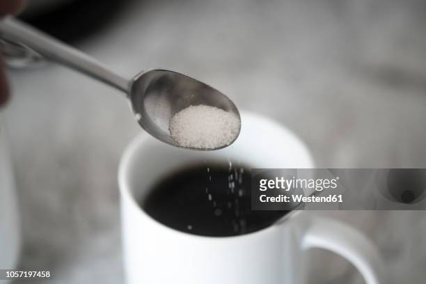 sugar on coffee spoon in front of mug with black coffee - sugar coffee - fotografias e filmes do acervo