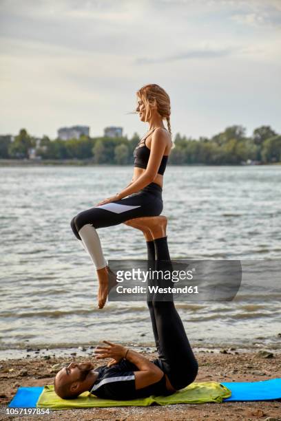 young man and woman practicing acro yoga - acroyoga stock pictures, royalty-free photos & images