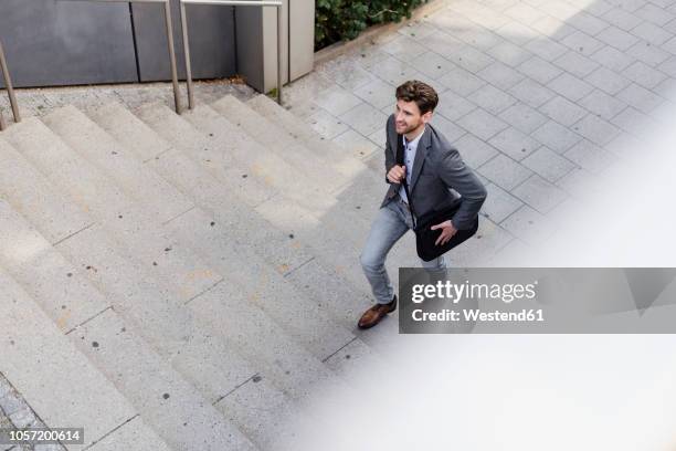 smiling businessman with crossbody bag walking upstairs - commuters overhead view stock pictures, royalty-free photos & images