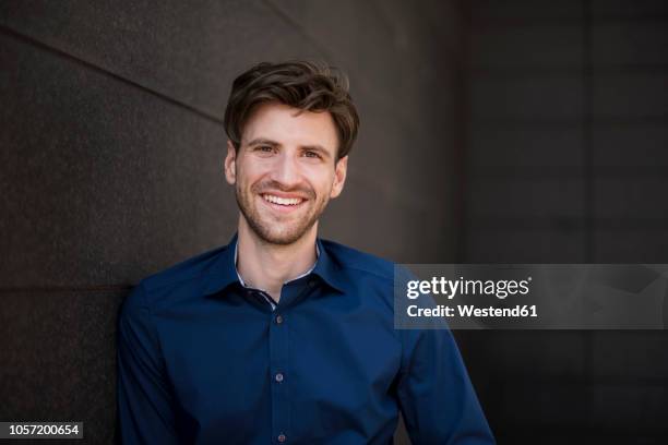 portrait of smiling businessman at a wall - well dressed young man stock pictures, royalty-free photos & images