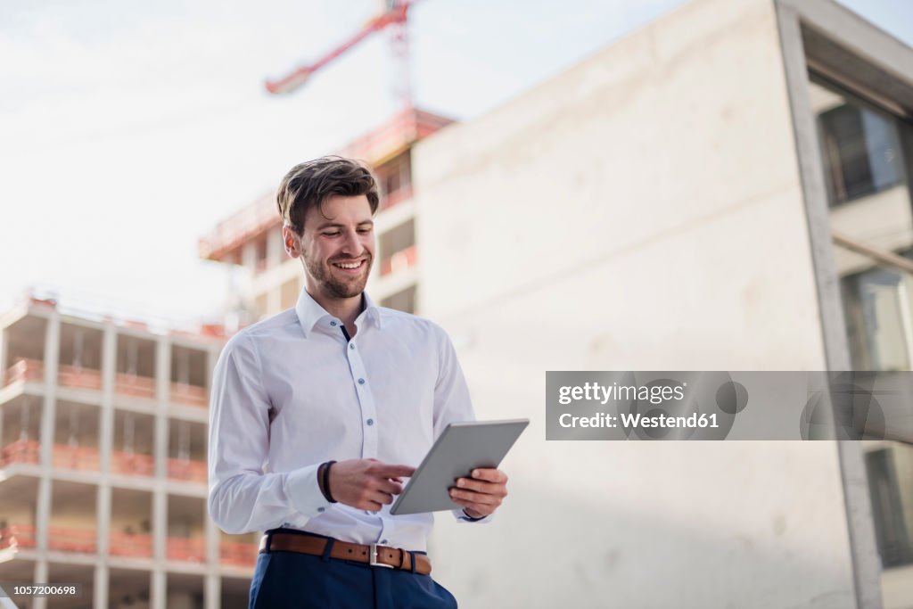 Smiling businessman in the city using tablet