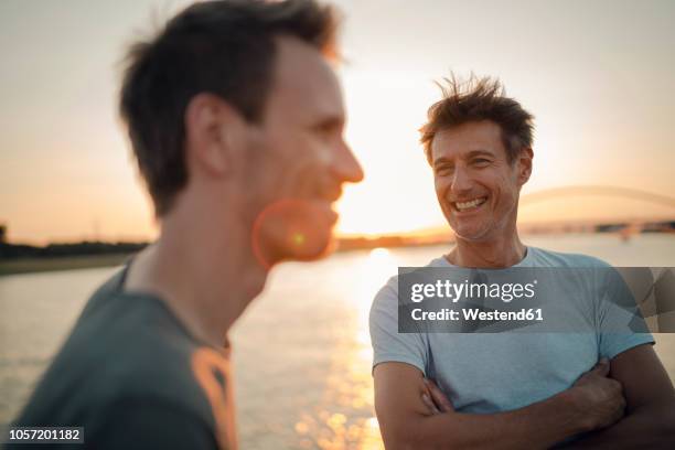 two friends meeting at sunset, spending the evening talking - smiling controluce foto e immagini stock