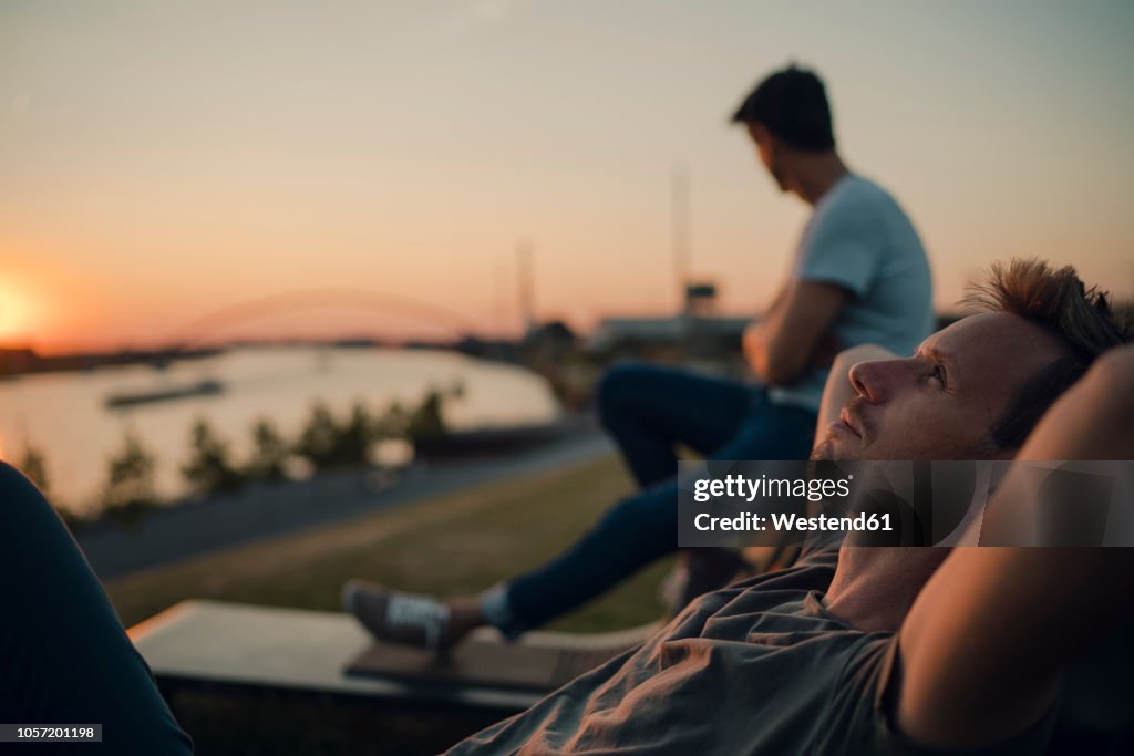 Two friends watching sunset at the river