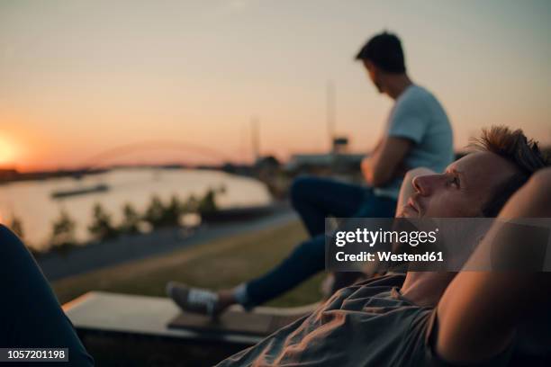 two friends watching sunset at the river - nordrhein westfalen fotografías e imágenes de stock