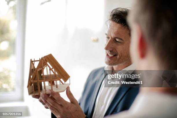 mature businessman sharing his knowledge with younger colleague - architekt modell stock-fotos und bilder